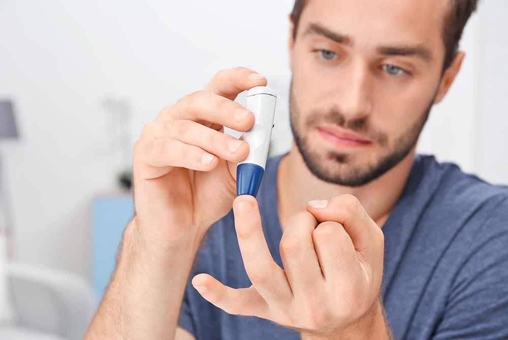 man testing blood sugar with lancet device